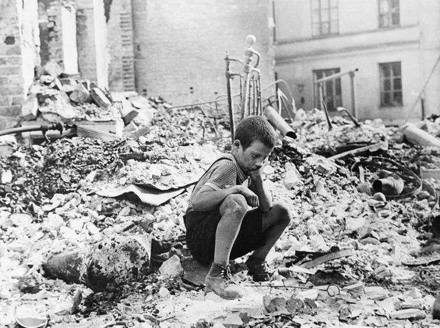 Un niño polaco vuelve a la que fue su casa y se pone en cuclillas entre las ruinas durante una pausa en los ataques aéreos alemanes en Varsovia