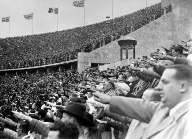 Espectadores en el estadio haciendo el saludo nazi