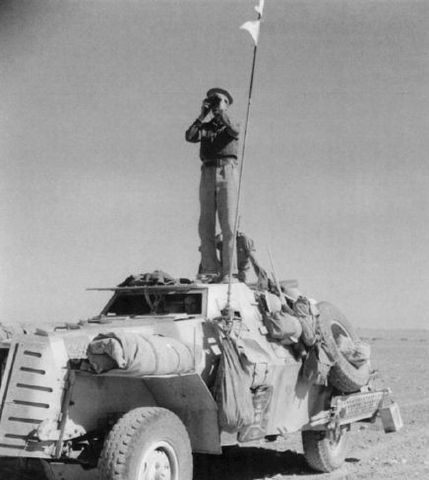 Oficial británico inspeccionando el frente sobre su vehículo blindado Marmon Herrington