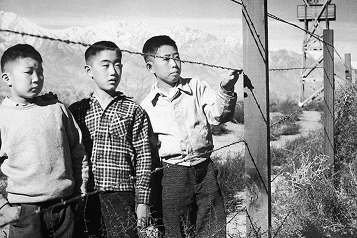 Niños de ascendencia japonesa junto a la valla de un campo de internamiento